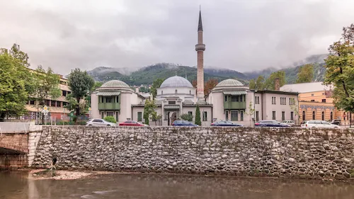 Bosnia and Herzegovina, Sarajevo - Beautiful view of the Emperor's Mosque on the banks of the Miljacka River with mountains in the background
