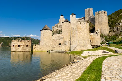 Serbia - Narrow channel of the Danube River flowing past high hills and Golubac Fortress, with towers built on rock ledges
