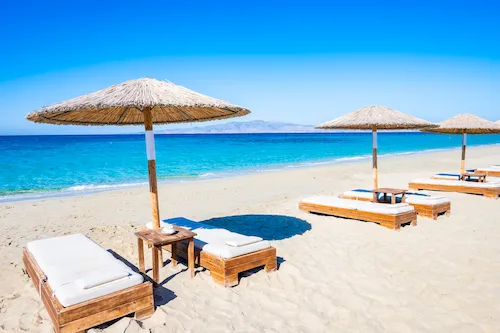 Greece, Naxos Island - Sun umbrellas on Plaka Beach with crystal clear sea water